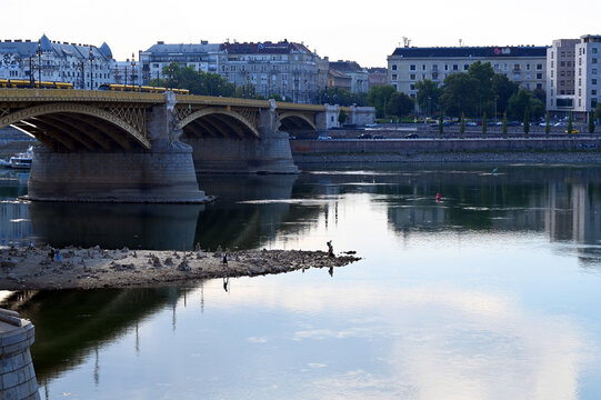 low water level on the Danube river at the Margaret Bridge in Budapest, Hungary. hot temperature, drought. exposed rocky island at the base of the bridge pillar. reflecting water. environment concept