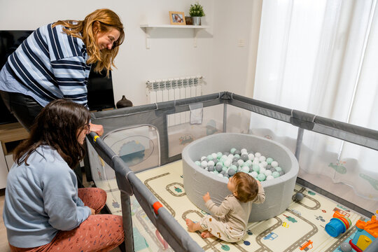 Family playtime with grandma and mother watching toddler