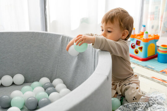 Toddler playing with balls in soft ball pit at home