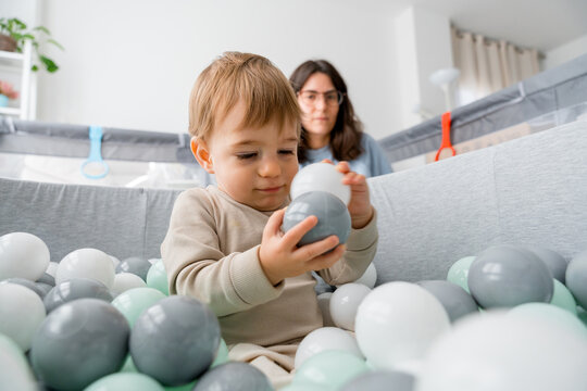 Toddler playing with soft balls at home under parent care