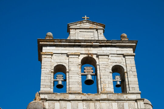 Church bell tower with three bells against clear blue sky