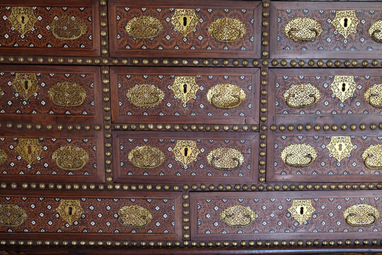 Antique wooden cabinet with ornate brass hardware pattern