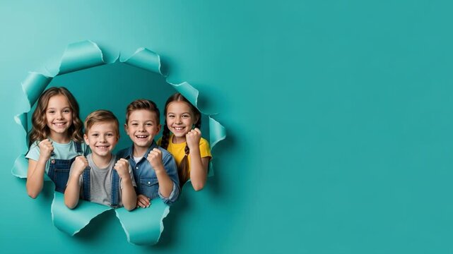 Four happy children posing through a torn paper hole