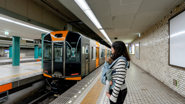 Mother with child waiting at train station in Osaka