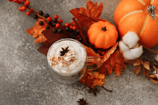 Warm drinks and fall decorations in a cozy cafe with pumpkin spice latte on a wooden table during autumn season