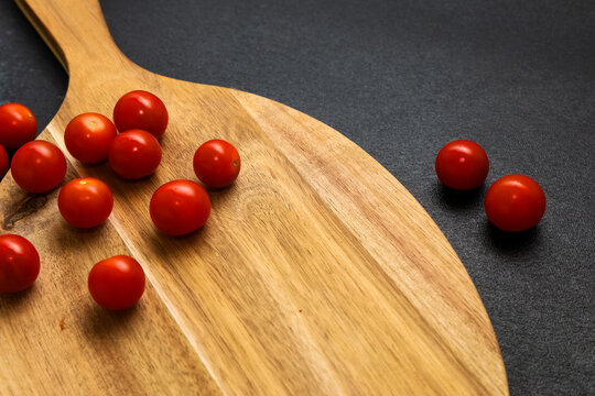 Tomatoes are placed on a wooden board with a dark background