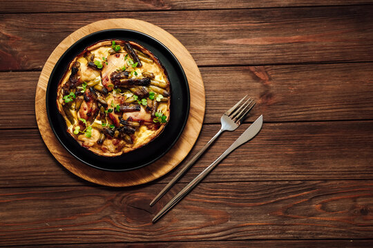 Delicious quiche served on a wooden board with fork and knife nearby