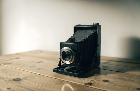 Vintage bellows camera rests on a wooden table antique