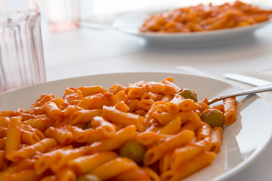 Pasta con salsa di pomodoro e olive verdi su piatto bianco