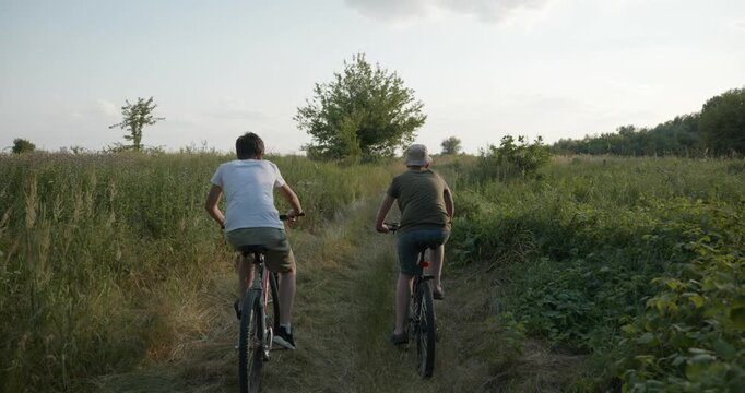 Two boys riding bicycles on nature. Teenagers spending time together. 4K 10-bit