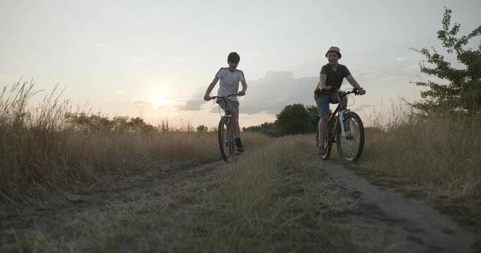 Two boys riding bicycles on nature. Teenagers spending time together. 4K 10-bit