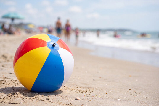 Colorful beach ball on sandy shore with blurred summer crowd for seaside background and summer banner design