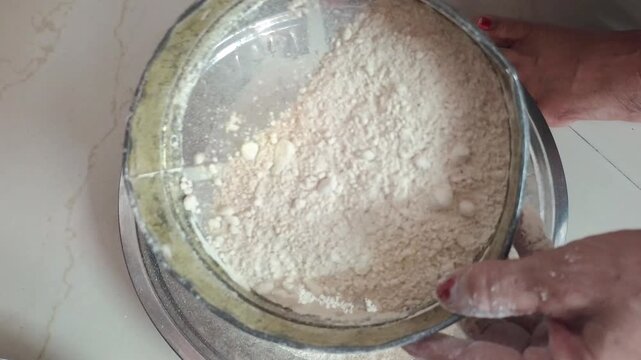 Close-up of woman hands sifting wheat flour and kneading dough in traditional dish