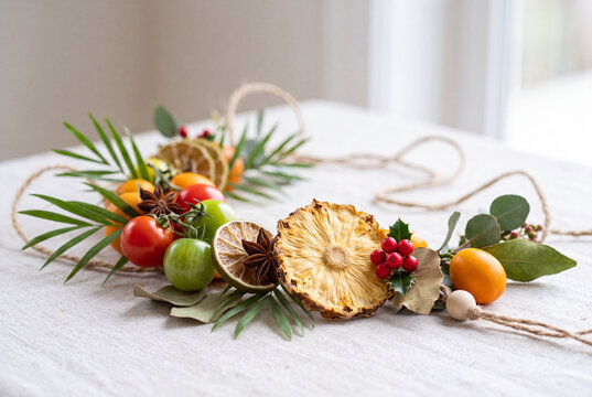 Tropical christmas table decoration with dried pineapple citrus foliage and festive berries for holiday centerpiece and seasonal decor background