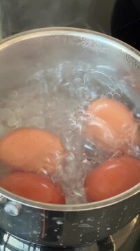 Two eggs boiling in a steel pot on the stovetop