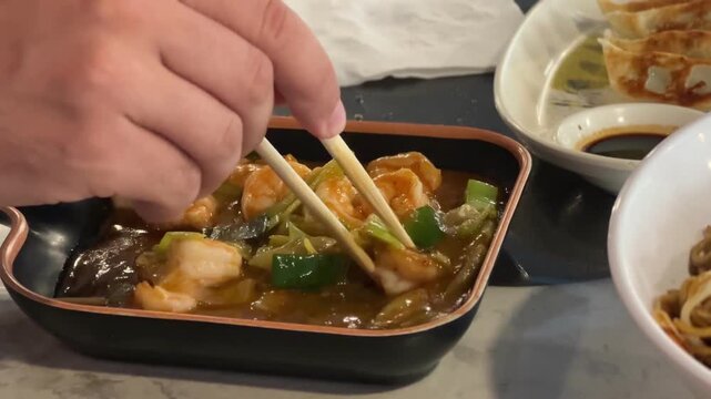 Shrimp in savory sauce with spring onions and chopsticks