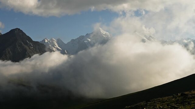 Majestic mountain peaks emerge from clouds during sunrise in scenic landscape