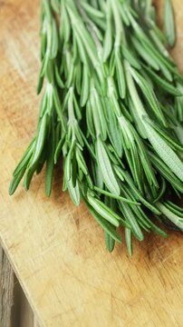 Vertical video. Fresh rosemary sprigs on wooden board. Seasoning.