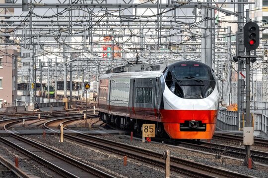 View of a modern limited express train arriving at Akihabara Station with overhead power lines and railway tracks in Chiyoda City, Tokyo, Japan.