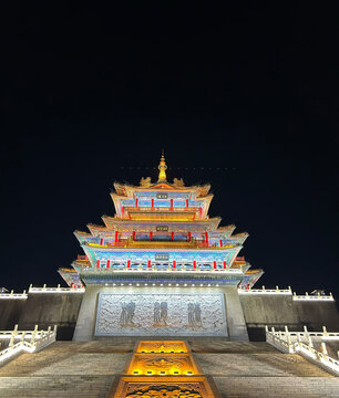 View of the illuminated Qingwei Tower featuring traditional Chinese architecture with intricate roof details and glowing lights against the night sky in Xianyang, Shaanxi, China.