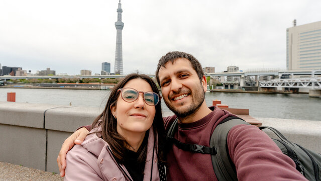 Tourist couple selfie with Tokyo Skytree by Sumida River