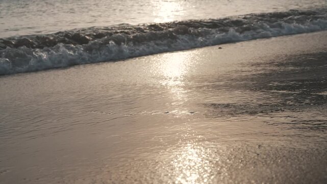 Low-Angle Close-Up of Calm Sea Waves Washing Golden Sand at Sunset