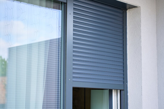 Roller shutter is partly closed over an exterior window on a modern house