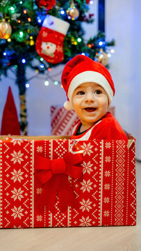 Smiling baby in Santa hat sitting in a festive gift box