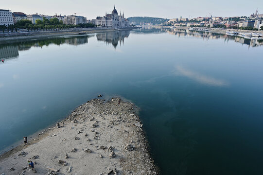low water level on the Danube river at the Margaret Bridge in Budapest, Hungary. hot temperature, drought. exposed rocky island at the base of the bridge pillar. reflecting water.