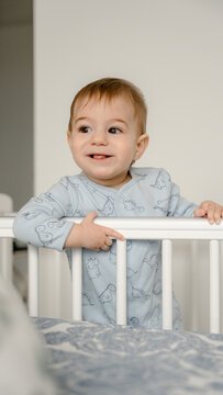 Smiling 9 month old baby standing in crib at home