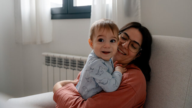 Mother cuddling baby boy at home for 9 month anniversary