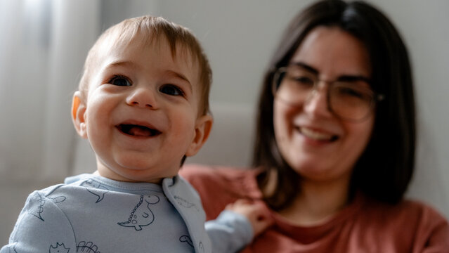 Smiling 9 month baby with mother at home in soft light