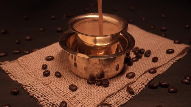 South Indian traditional hot filter coffee in a traditional brass cup and coffee beans background
