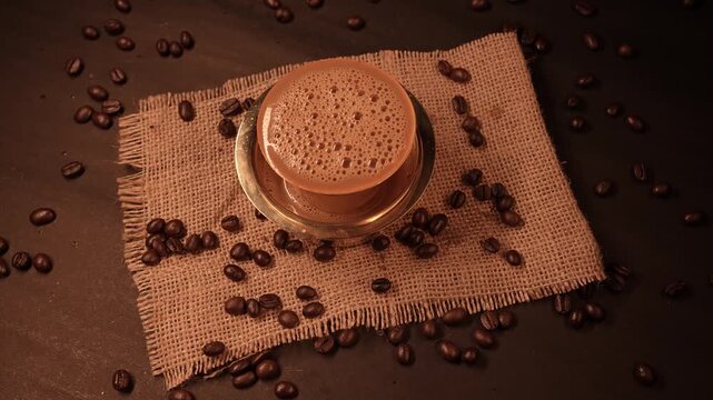 A traditional south indian Brass cup of coffee in beans background