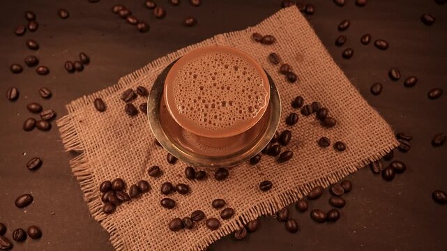 A traditional south indian Brass cup of coffee over beans background