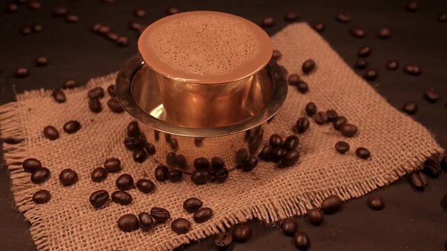 Traditional south indian Brass cup of coffee over beans background