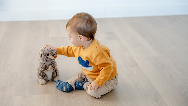 Toddler playing with stuffed toy on home floor