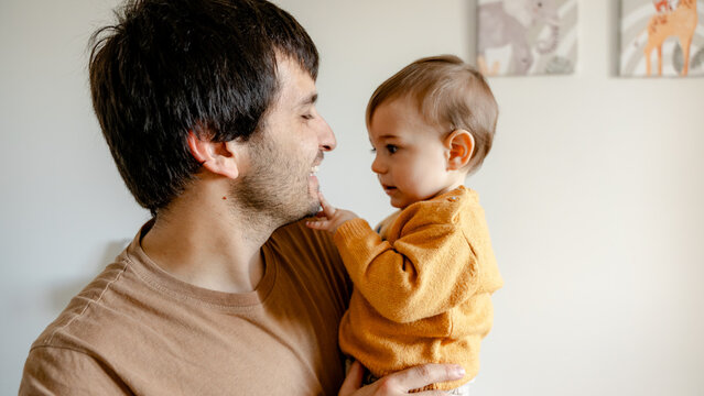 Father holding baby at home, sharing a tender moment