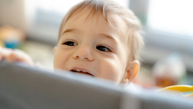Baby smiling in playpen at home with colorful toy