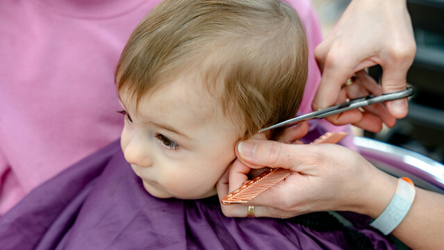 Toddler getting haircut at salon with scissors and comb