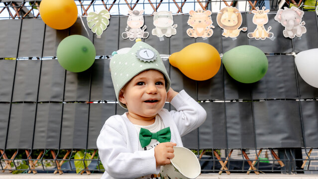 One-year-old baby at first birthday party with balloons
