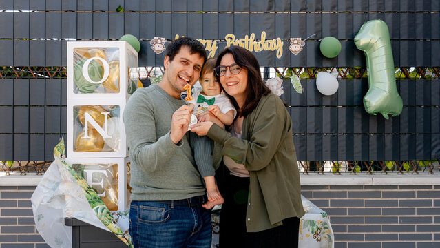 Family with baby celebrating first birthday with 1 balloon