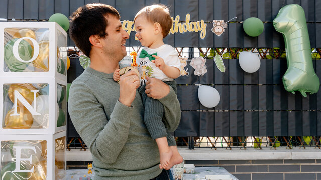 Father holding baby at first birthday party with number ONE