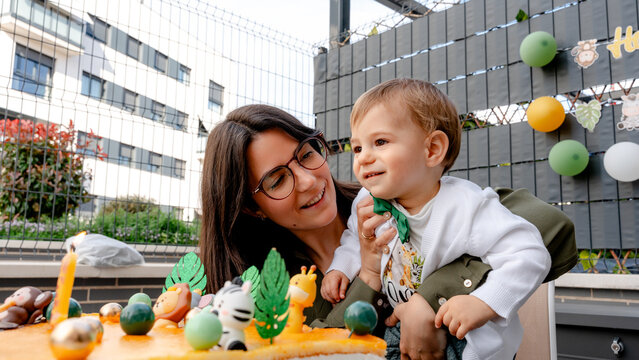 Mother and baby celebrate first birthday with cake outdoors