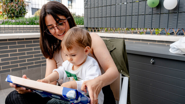 Mother and baby opening gift at first birthday party