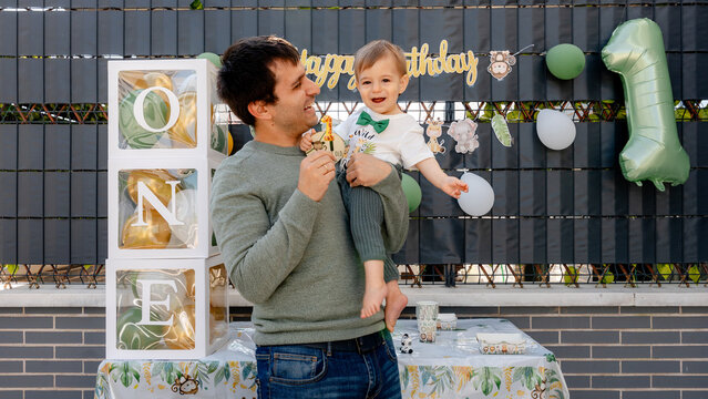 Father holding baby at first birthday party with number ONE