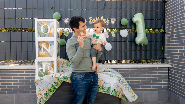 Father holding baby at first birthday with ONE year decor