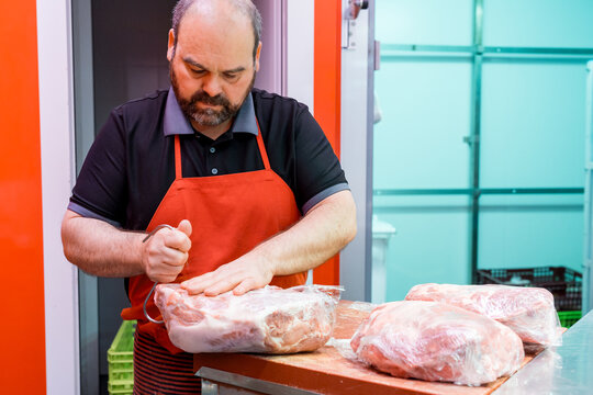 Butcher trimming fresh meat on cutting table in shop