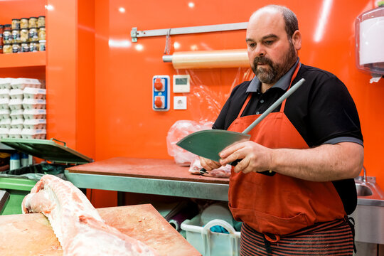 Butcher sharpening knife in shop preparing fresh meat cut