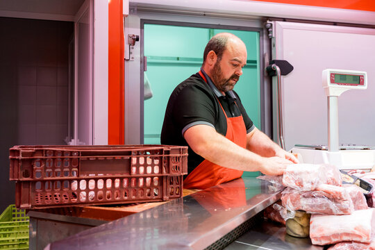 Butcher wrapping fresh meat at counter in local butcher shop